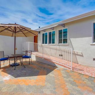 A sunny backyard patio with an umbrella, table, and chairs.