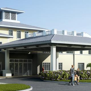 A modern building entrance with people walking outside on a sunny day.