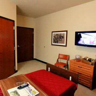 Cozy hotel room interior with a bed, television, and wooden furniture.