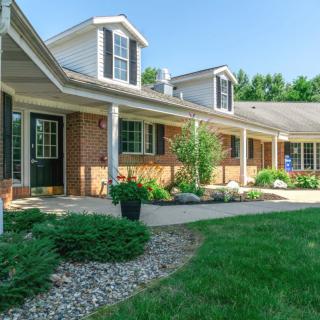 A charming suburban brick house with a landscaped front yard and a welcoming porch.