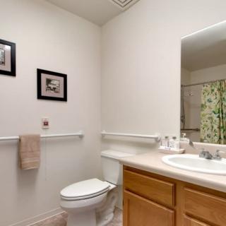 A clean and neatly organized bathroom with a toilet, sink, and mirror.