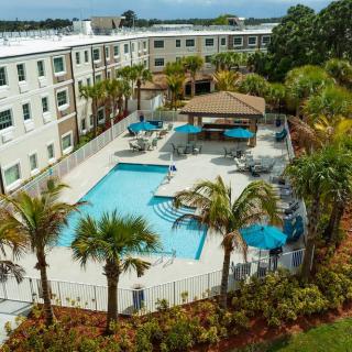 Aerial view of an apartment complex with a swimming pool and palm trees.