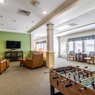 A spacious game room featuring a foosball table, comfortable seating, and a television for entertainment.