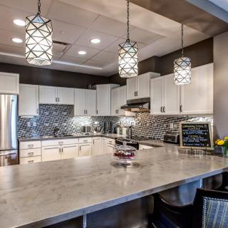 A modern kitchen with pendant lighting, featuring white cabinets and a patterned backsplash.