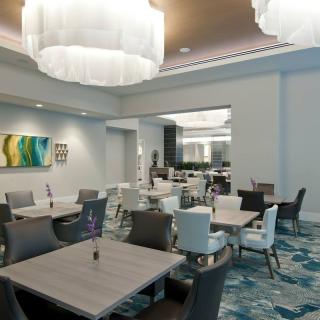 A modern dining area featuring elegant furniture, contemporary lighting, and colorful artwork.