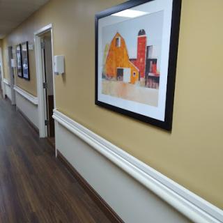 A hallway featuring a colorful framed artwork against yellow walls, complemented by wooden flooring.