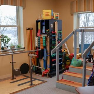 A physical therapy room equipped with exercise tools and parallel bars.