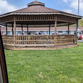 A beautifully designed wooden gazebo surrounded by green grass, perfect for outdoor gatherings.