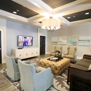 A modern living room with elegant interior design, featuring a chandelier, comfortable seating, and a mounted television.