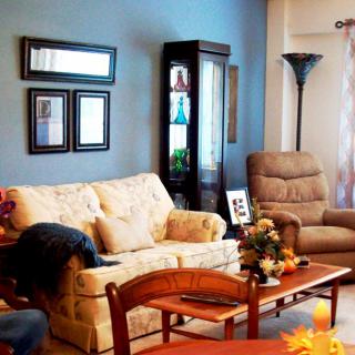 A cozy living room with a sofa, armchair, and wooden coffee table, set against a blue accent wall.