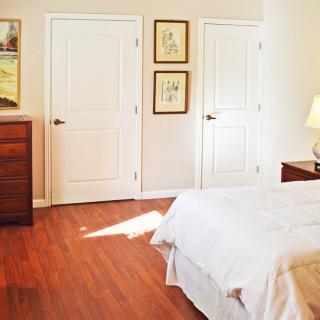 A cozy bedroom with a wooden floor, featuring a bed and dresser.