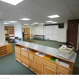 A reception area with a desk and waiting space, featuring office furniture and shelving.