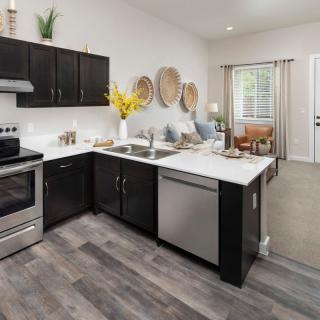 A modern kitchen with sleek black cabinets, stainless steel appliances, and stylish decor.