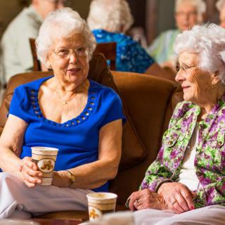 Two elderly women enjoying conversation over coffee indoors.