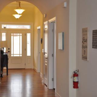 A well-lit hallway with wooden flooring leading to a door.