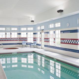 An indoor swimming pool with tiled walls and large windows.