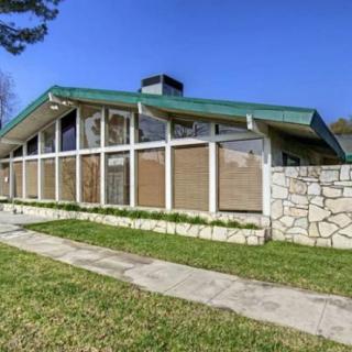 A mid-century modern house with large glass windows and a green roof.