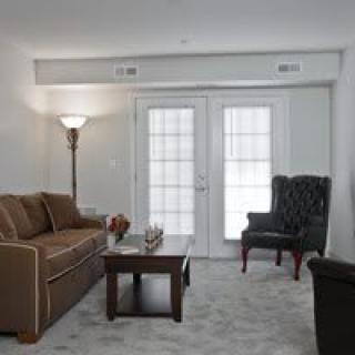 A cozy living room with a sofa, armchair, and coffee table near French doors.