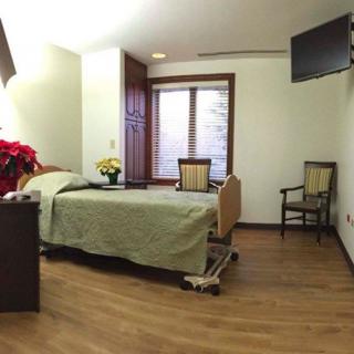 A well-lit hospital room with a single bed, television, and window.