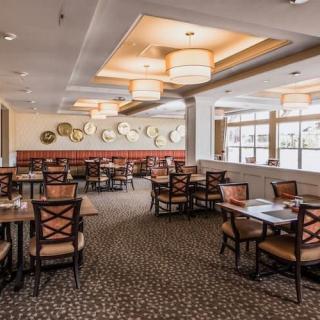 A spacious and well-lit restaurant dining area with neatly arranged tables and chairs.