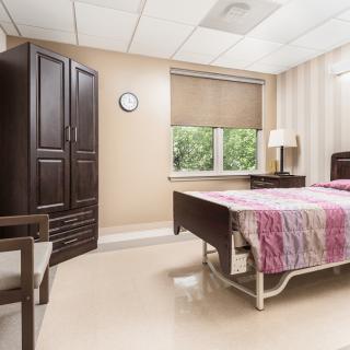 A hospital room with a bed, wardrobe, and window view.