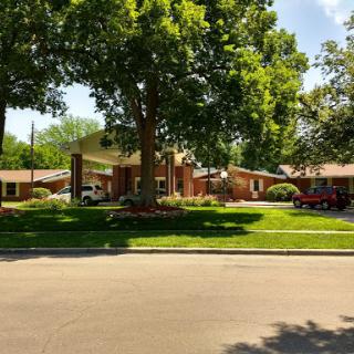 A serene residential setting featuring a well-maintained building surrounded by lush greenery.