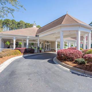 An elegant building entrance with columns and a well-maintained driveway.