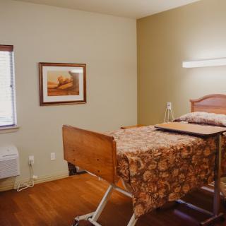 A hospital room with a single bed and artwork on the wall.