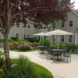 A peaceful garden patio with outdoor seating and umbrellas next to an apartment building.