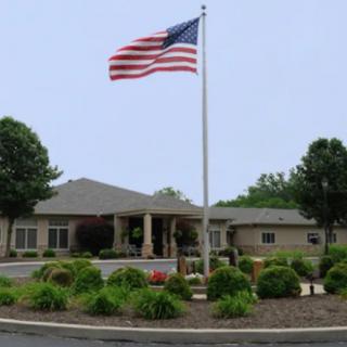 A building with an American flag in front, surrounded by landscaped bushes and trees.