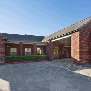 A brick building with an entrance and a driveway under a clear blue sky.