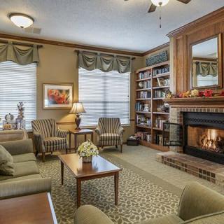 A cozy living room featuring comfortable seating, a warm fireplace, and bookshelves filled with books.