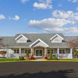 A suburban house with traditional architecture and a landscaped front yard under a blue sky.