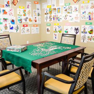 A cozy game room with a puzzle set up on a table, surrounded by chairs and colorful artwork on the walls.