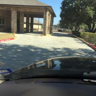 A view from a vehicle approaching a building on a sunny day.
