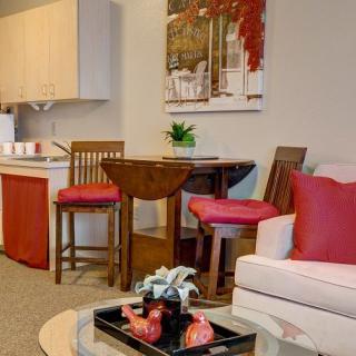 A cozy living room with a dining area, featuring red accents and modern decor.