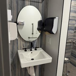 A modern restroom featuring a sleek sink, mirror, and hand dryer.