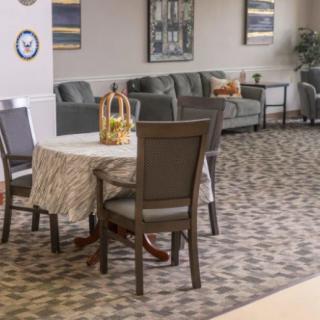 A cozy waiting area with a table and chairs set on a patterned carpet.