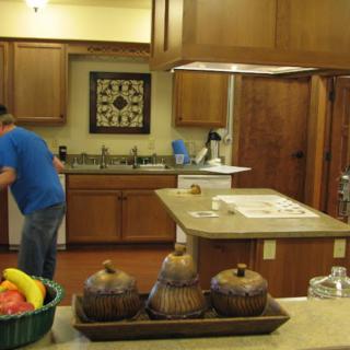 A modern kitchen interior with a central island, wooden cabinets, and a fruit basket on the counter.