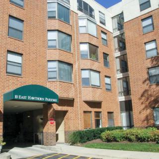 A multi-story brick apartment building with an entrance canopy.