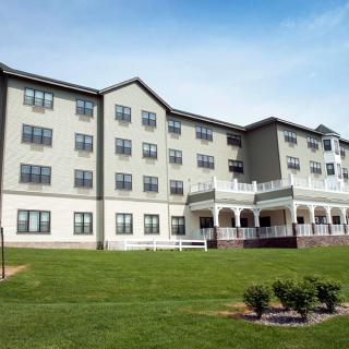 A multi-story residential building with a well-maintained lawn and outdoor porch area.