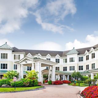 A grand, white building surrounded by lush gardens under a blue sky.