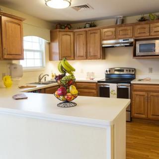 A cozy kitchen with wooden cabinets, a white countertop featuring a fruit basket, and modern appliances.