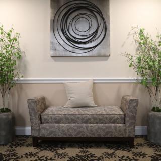 A modern waiting area with a stylish sofa, decorative plants, and abstract wall art.