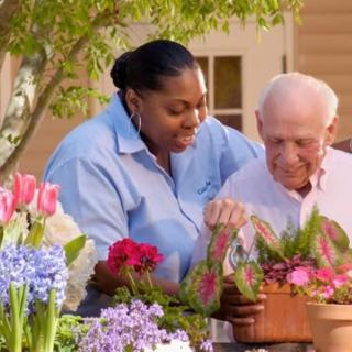 Two people tending to flowers in a garden setting.