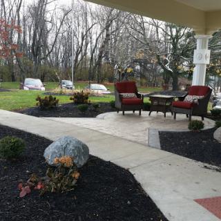 A cozy outdoor patio area with comfortable seating, surrounded by a well-maintained garden.