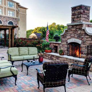 A cozy outdoor patio with a stone fireplace and comfortable seating.