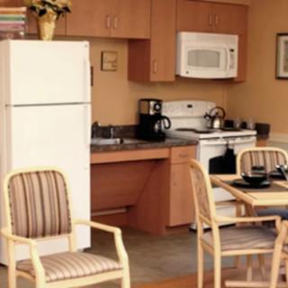 A cozy kitchen with dining area, featuring appliances like a refrigerator, microwave, and oven.