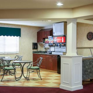 A cozy breakfast area featuring a dining table, chairs, and a beverage station in a well-lit environment.