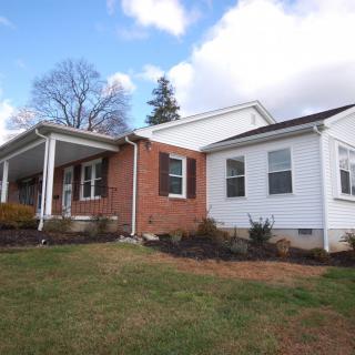 A suburban house with a brick and white exterior under a cloudy sky.